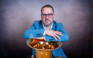 Patricio Cosentino holding his tuba, smiling.