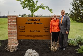 Chris Burns-DiBiasio and Dan DiBiasio standing by the new DiBiasio Athletics Complex sign.