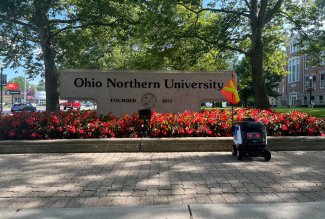 Kiwibot positioned next to sign at Ohio Northern University.