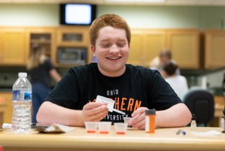 An Ohio Northern University Pharmacy summer camp participant sitting at a table with liquid medicines.