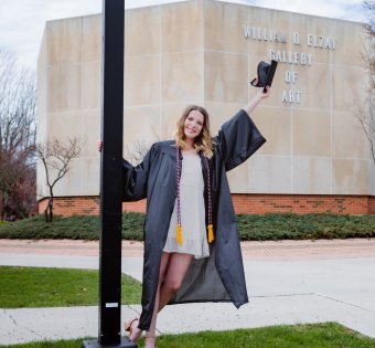 Person in cap and gown leaning off a lamp post